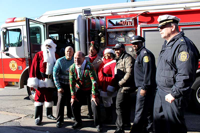 Patrick Burns, third from left, poses for a photo alongside local elected officials, members of the Philadelphia Fire Department, community leaders and Santa and Mrs. Claus before boarding a fire truck to make holiday meal deliveries to firefighters.    