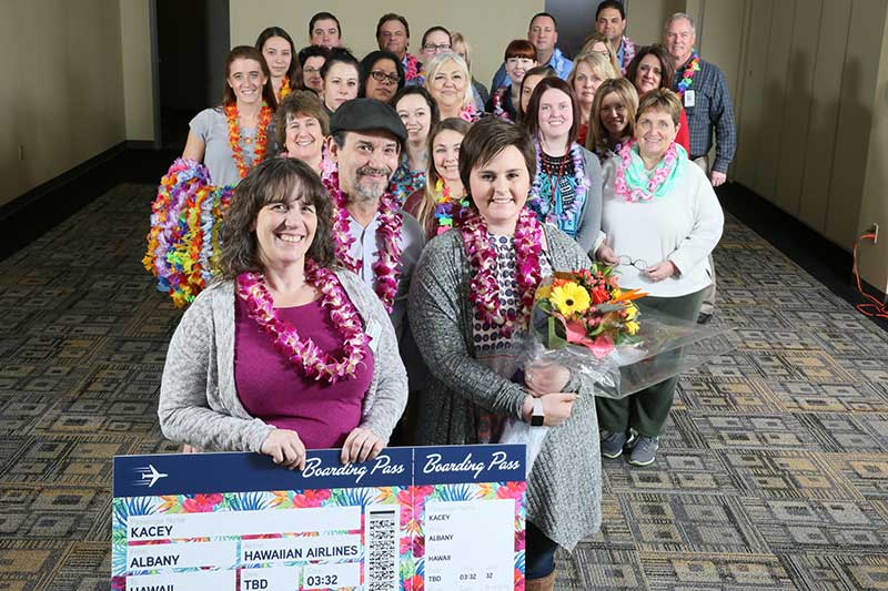 Price Chopper-Market 32 staff surround Make-A-Wish teen Kacey, right with bouquet, before her trip to Hawaii.