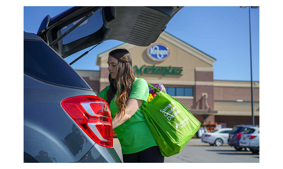 An Instacart shopper loading a car in a Kroger parking lot.