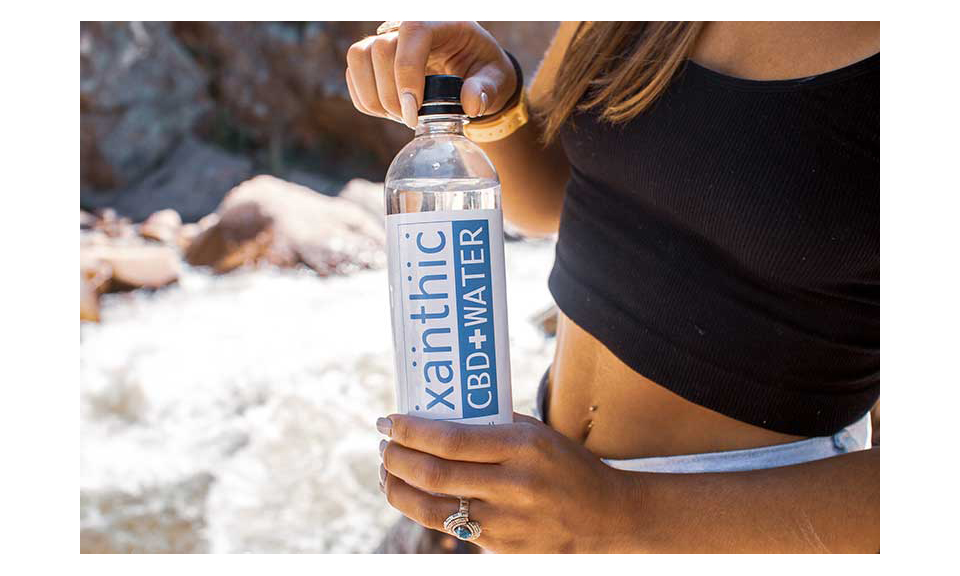 A woman holding a bottle of Xanthic CBD Water