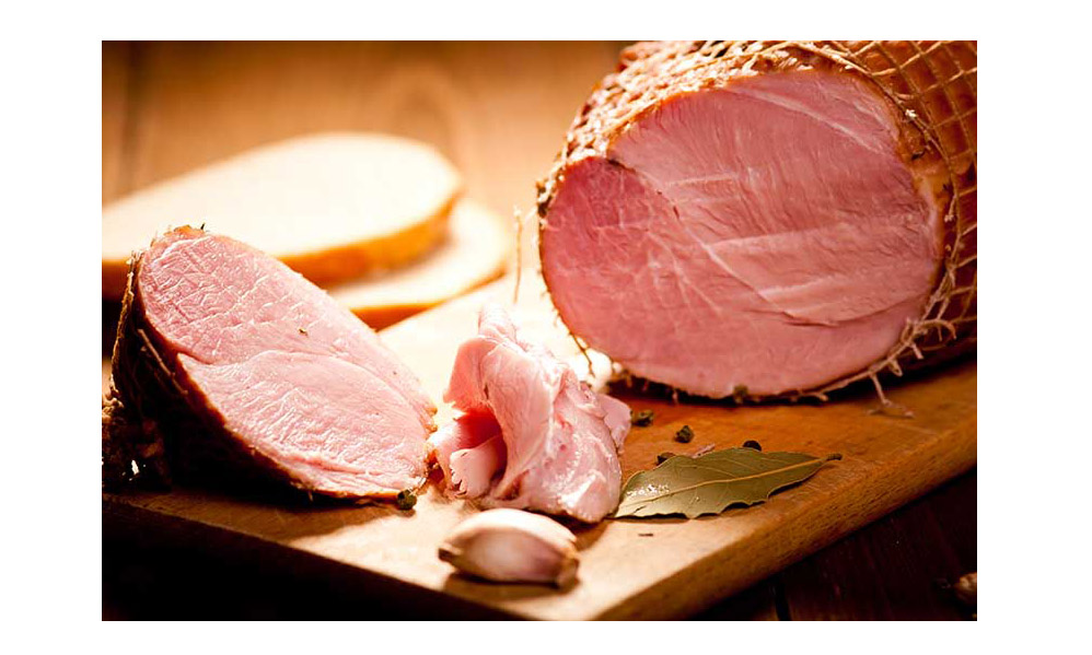 A whole ham partially sliced on a cutting board