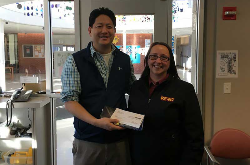 Jen Tomer, team leader of VERC East Acton Mobil, presents a check for $500 to Andrew Shen, principal of R.J. Grey Junior High School in Acton.