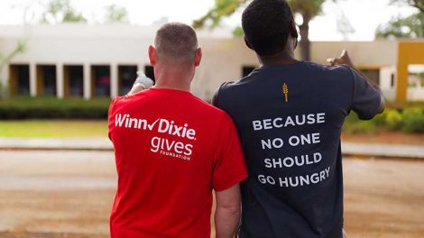 A Winn-Dixie and Feeding America representative show off their promotional t-shirts