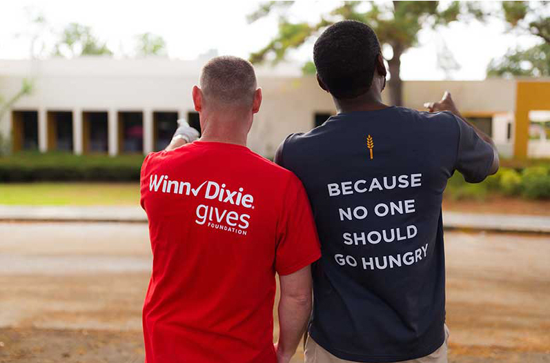 A Winn-Dixie and Feeding America representative show off their promotional t-shirts