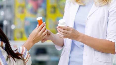 Cropped shot of pharmacist and customer holding containers with medication in drugstore, DIR fees