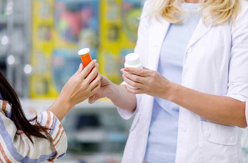 Cropped shot of pharmacist and customer holding containers with medication in drugstore, DIR fees