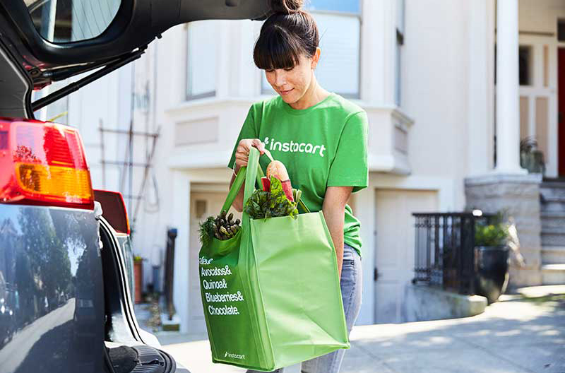 An Instacart shopper with a bag of groceries