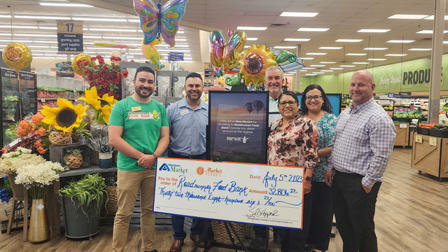 Representatives from Roadrunner Food Bank and Albertsons Markets hold a check.