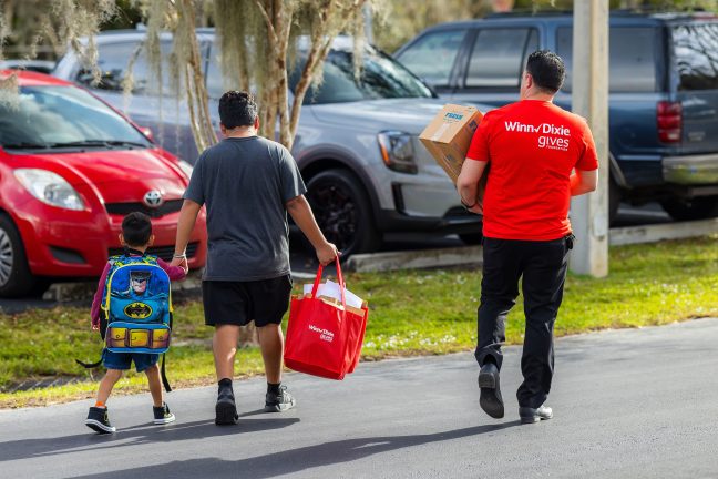 Southeastern Grocers employee helps family load grocery donations in their car.