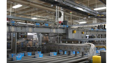 Image of the interior of a Kellanova manufacturing facility, with several blue boxes of product running down automated grey production lines.