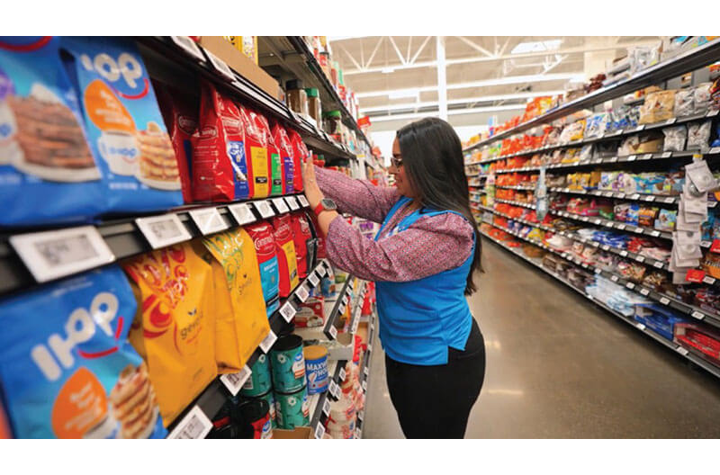 Image of Walmart employee in an aisle with digital shelf labels