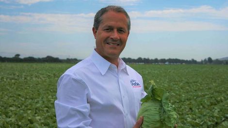 Image of Rick Alcocer holding head of lettuce in a field