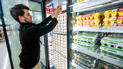 Meijer employee stocking shelves in refrigerator highlighting the grocer's reduction in refrigerant emissions rates.