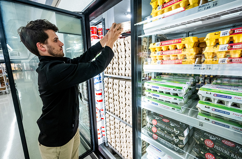 Meijer employee stocking shelves in refrigerator highlighting the grocer's reduction in refrigerant emissions rates.