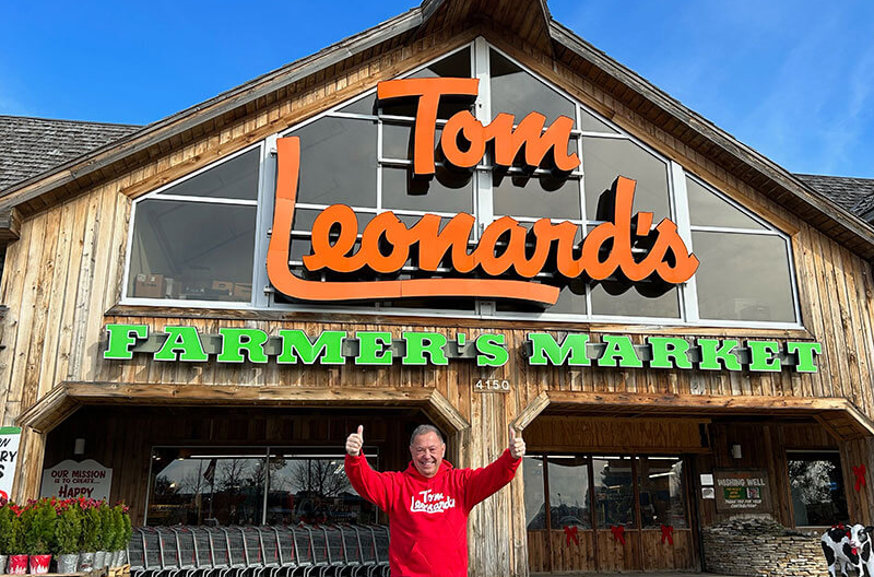 image of exterior of Tom Leonard's Farmers Market with Tom Leonard in foreground