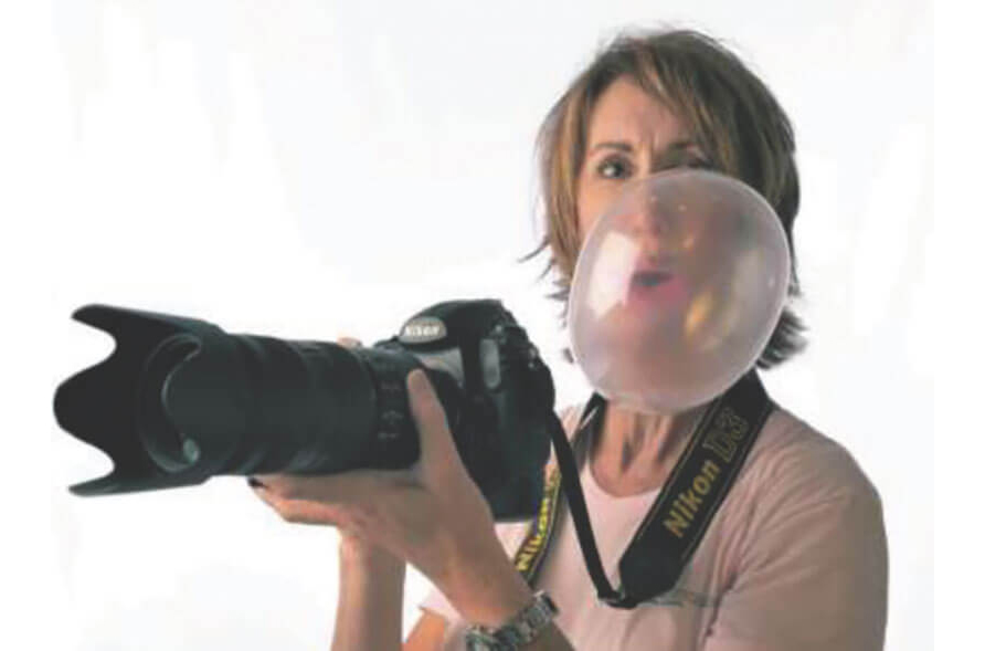 image of Donna Simpson holding a camera and blowing a bubble