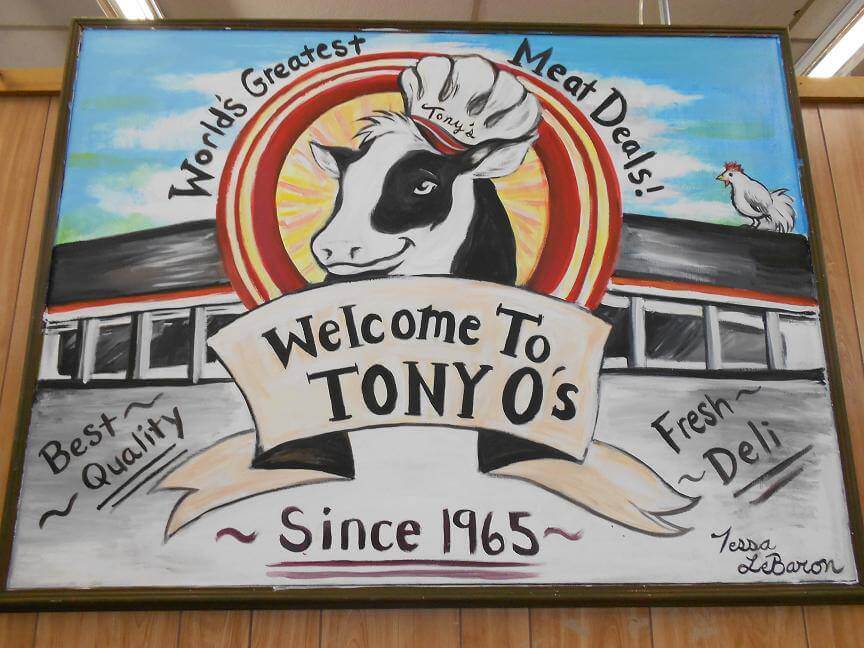 handpainted sign with cow in chef's hat welcoming shoppers to Tony O's