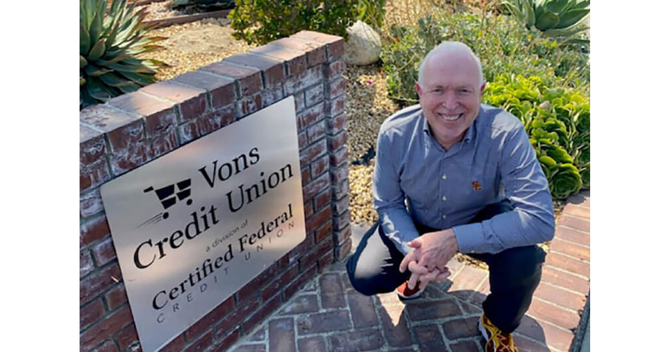 photo of Steve Weakley, CEO of Certified Federal Credit Union, kneeling by sign outside of office