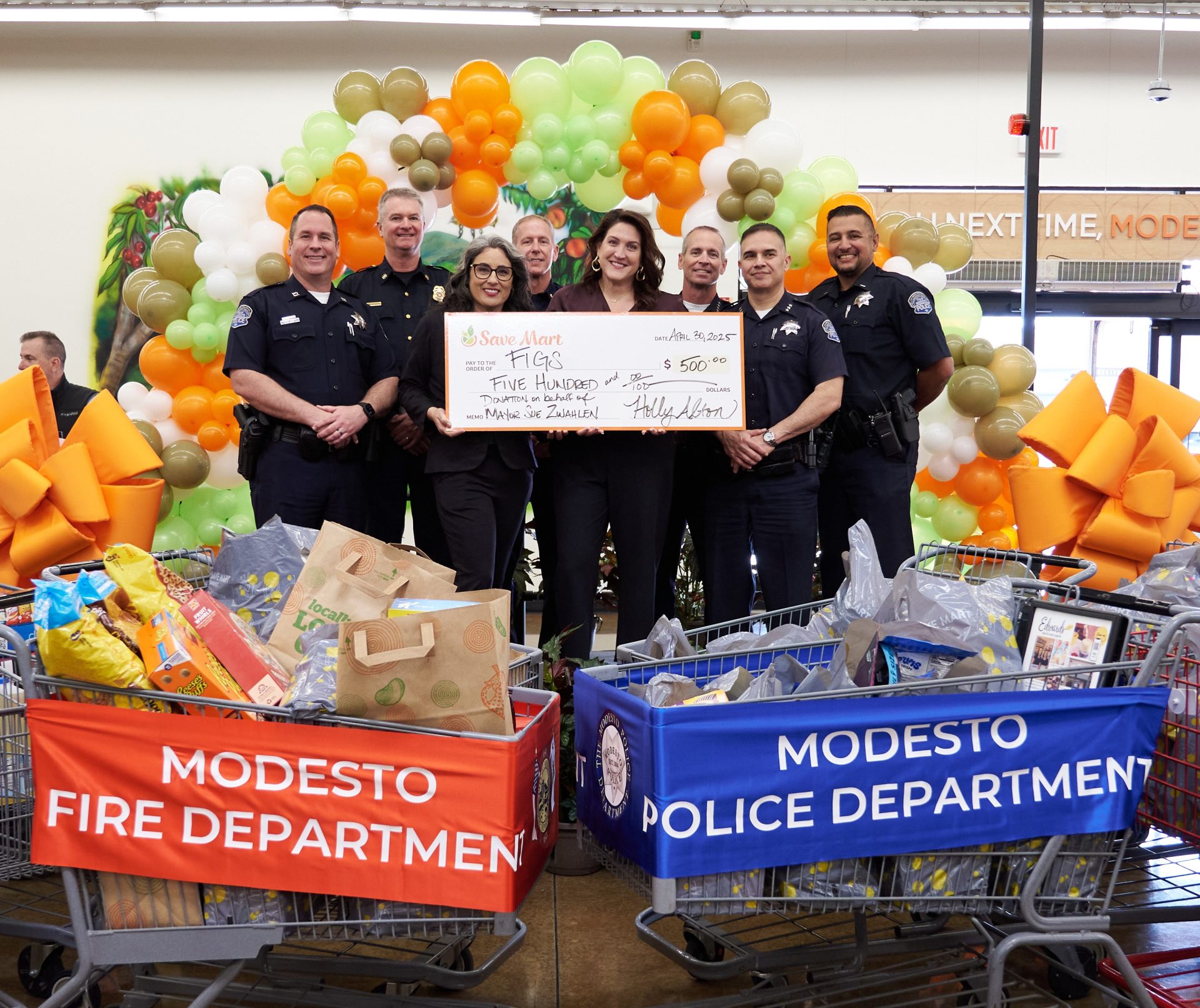 After an exciting “Supermarket Sweep” between Modesto’s bravest and finest during the Save Mart Modesto store Grand Reopening event on Wednesday, April 30, competitors were on hand to present a $500 check and $4,140.78 in groceries to Food Initiative of Greater Stanislaus (FIGS) on behalf of Modesto Mayor, Sue Zwahlen. (L to R: Captain Chris Adams, MPD; Deputy Chief Darin Jesberg, MFD; Store Manager, Holly Alton; Chief Kevin Wise, MFD; Anna Ennis, Food Initiative of Greater Stanislaus; Chief Brandon Gillespie, MPD; Assistant Chief Ivan Valencia, MPD; Lieutenant Kalani Souza, MPD. Photo credit: Alfonso Rojas, Rojas Photography