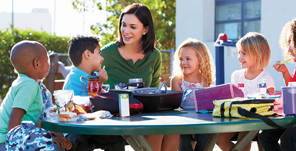 image of adult woman and several children sitting around table in celebration of back to school