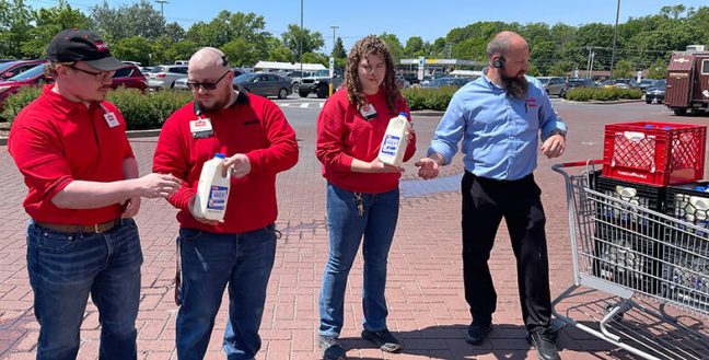 image of people in line passing milk jugs to fill crates for donation