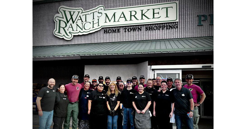 group photo of employees and firefighters in front of Watt's Ranch Market in Meeker, CO, a banner of Clark's Market