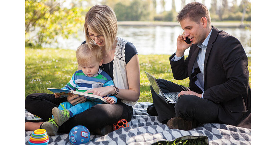 photo of young family sitting on blanket in front of lake