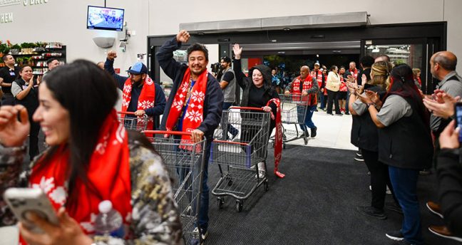 photo of customers entering new H-E-B store in San Antonio, pushing carts and waving