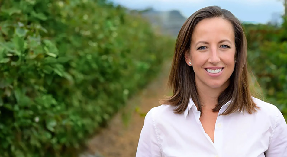 photo of Brie Reiter Smith in foreground with berry bushes and dirt road in background