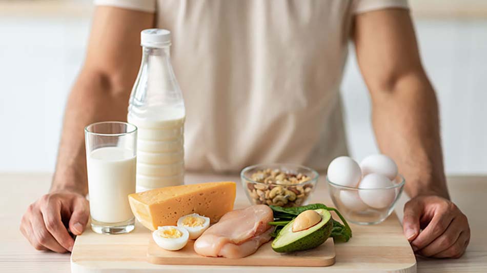 cropped view of young guy standing in front of protein rich foods on table
