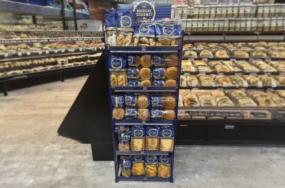 Brioche Gourmet floor display of packaged brioche positioned next to a grocery store in-store bakery case