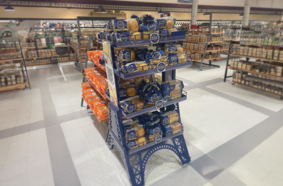 Eiffel Tower-shaped Brioche Gourmet metal display rack stocked with packaged brioche in a grocery store aisle